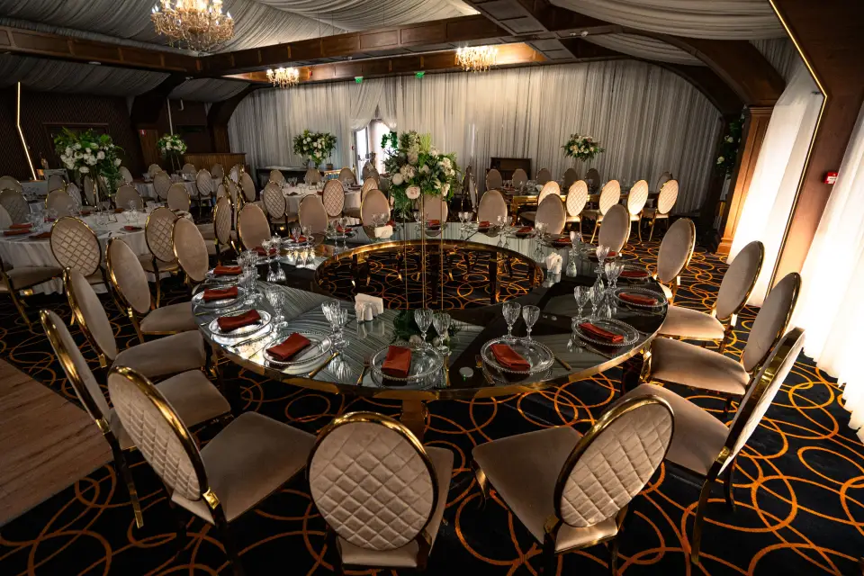 Grand Event Ballroom aranjat de nuntă, cu mese rotunde, scaune aurii și perdele luminate